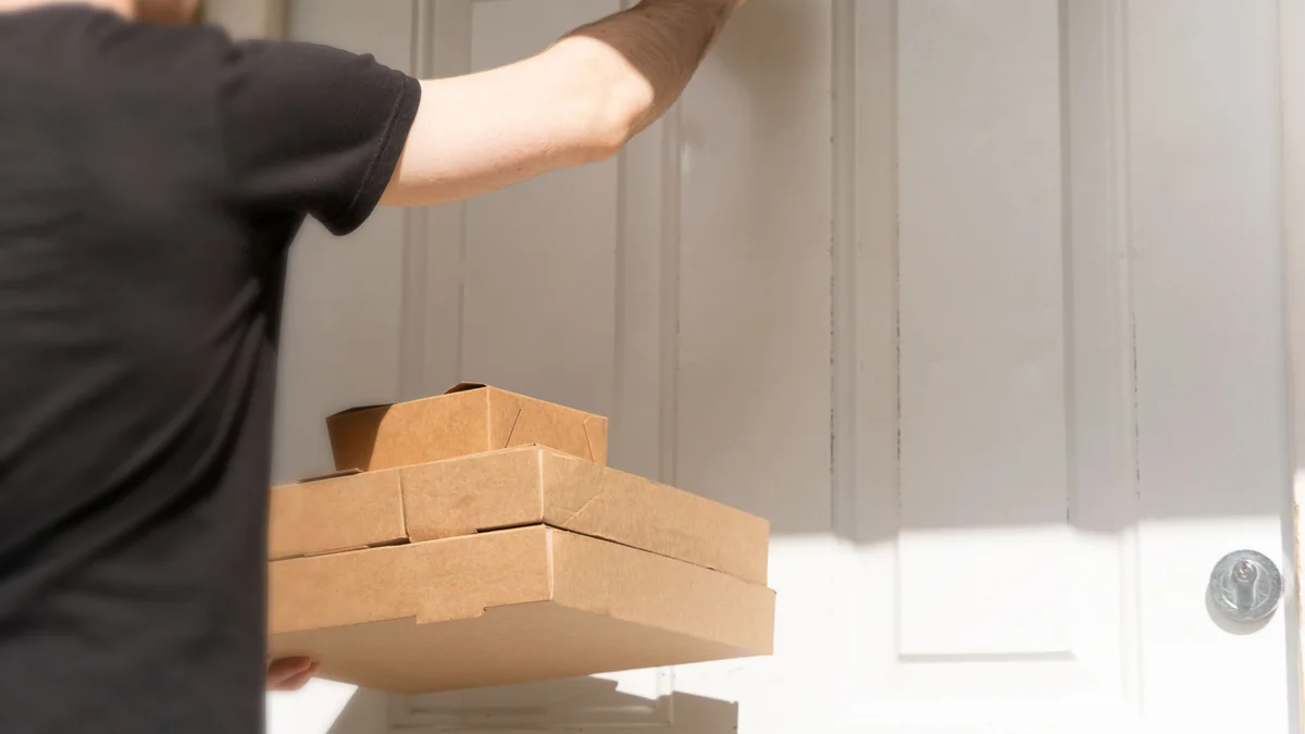 Entregador com caixas em frente à porta de um cliente durante uma entrega